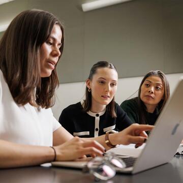 Three students looking at a laptop