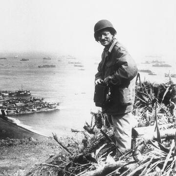 Photographer in fatigues on top of a cliff overlooking the sea