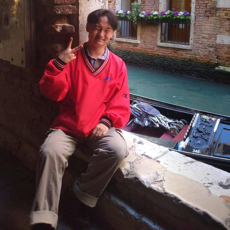 Student flashes a peace sign while sitting near a canal