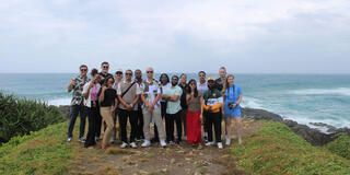 group of students pose on mountain overlooking ocean