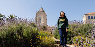 student walks along floral pathway on usf campus