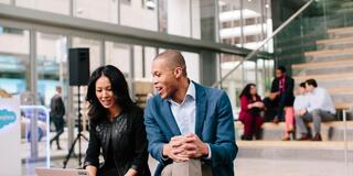 two emba students in front of a computer