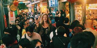 Person flashes a peace sign in the midst of a busy marketplace