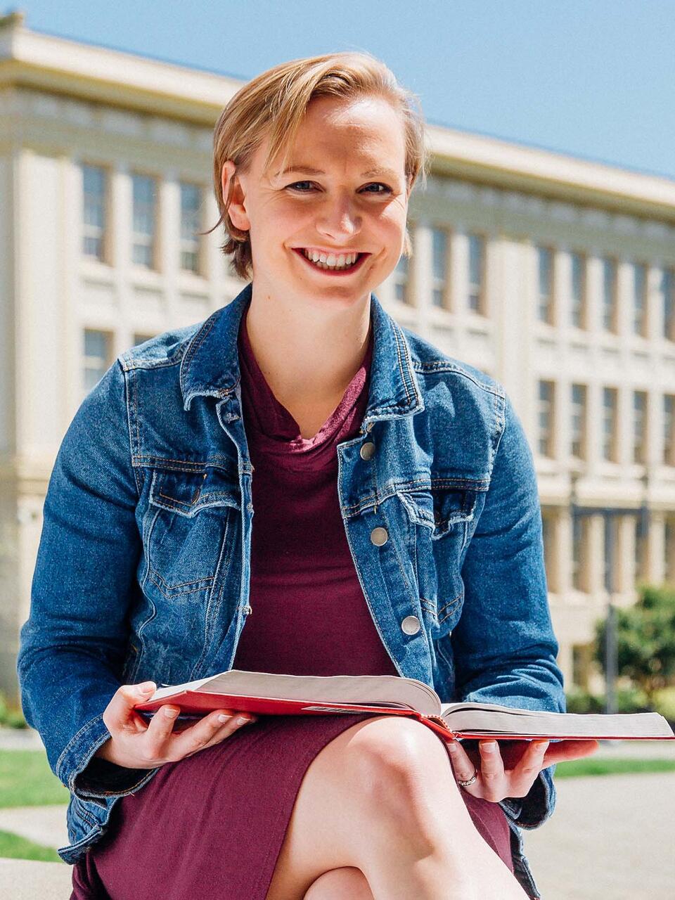 Student sitting in the sun with a book.