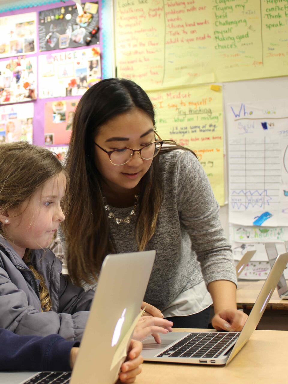 Student helping two children with their computers